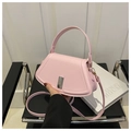Chic light pink crescent crossbody bag with silver metallic buckle on a stylish leather chair - Pink