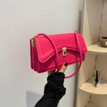 Pink faux leather shoulder bag with gold hardware lock shown in hand by model - Rose Pink