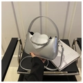 Detail der silbernen Metallhandtasche mit herzförmiger Klappe und polierter Perlenkette - Silber