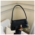 Detalle de un bolso baguette de charol negro brillante con hebilla metálica elegante - Negro