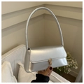 Detalle de un bolso baguette plateado con acabado metálico y hebilla dorada elegante - Plateado