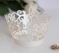 Macro shot of laser-cut white lace cupcake wrapper with heart and swirl patterns - Ivory