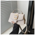 Detail of beige pebbled leather handbag featuring a large textured gold oval metal buckle - White