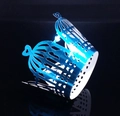 Detail of laser-cut blue metallic cupcake wrapper featuring hollow birdcage and heart motifs - Reflective Blue