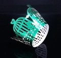 Macro view of green birdcage lace cupcake wrapper with heart handle on black background - Reflective Green