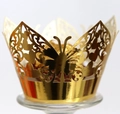 Macro shot of gold laser-cut cupcake wrapper with butterfly pattern and metallic finish - Reflective Gold