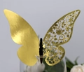 Close-up of golden laser-cut butterfly place card with floral patterns on glass rim - Reflective Gold