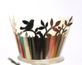 Macro-opname van zilveren lasergesneden cupcake wrapper met vogels en bladeren - Reflecterend Zilver