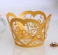 Detailed macro view of gold laser-cut heart pattern cupcake wrapper for wedding events - Gold