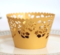 Macro shot of gold laser-cut cupcake wrapper with floral patterns and a chocolate ball - Gold