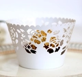 Close-up of white laser-cut rose hollow cupcake liner with a gold foil chocolate - White