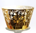 Close-up of golden laser-cut Halloween cupcake wrappers with skull and tree branch patterns - Reflective Gold