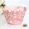 Macro shot of laser-cut floral pattern on pink pearlescent cupcake wrapper for weddings - Pink