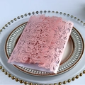 Carte d'invitation rose découpée au laser avec motifs floraux posée sur une assiette vintage - Rose