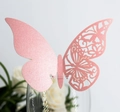 Detailed view of pink laser-cut butterfly card with floral patterns on a glass rim - Pink