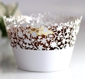 Macro shot of white laser-cut cupcake wrappers with floral patterns and pearl finish - White