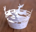 White laser-cut Christmas reindeer cupcake wrappers on dark wood table - White
