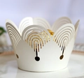 Macro view of white laser-cut paper cupcake wrappers featuring elegant wavy edge patterns - Ivory
