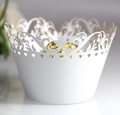 Macro shot of white laser-cut cupcake wrapper with heart patterns and intricate filigree - White