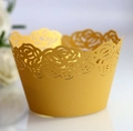 Close-up of laser-cut rose hollow pattern on golden cupcake wrappers for wedding decor - Gold Yellow