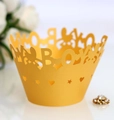 Macro shot of laser-cut cupcake wrapper featuring boy letters and rabbit silhouettes - Gold