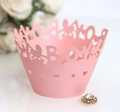 Macro detail of laser-cut pearl pink cupcake wrapper with BOY text and crown design - Pink
