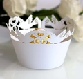 Macro shot of laser-cut wedding cupcake wrapper with heart and dove patterns - White