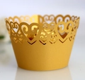 Macro detail of laser-cut heart pattern on golden pearlescent cupcake wrappers - Gold