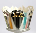 Macro detail of silver laser-cut cupcake wrapper with hollow heart and bird patterns - Reflective Silver