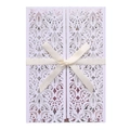 Detail of white laser-cut wedding invitation with elegant ribbon bow and floral motif - White