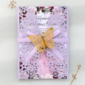 Close-up of laser-cut lavender wedding invitation with gold butterfly and purple ribbon - Lilac