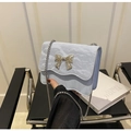 Nahaufnahme der hellblauen Faltenhandtasche mit goldener Schleife und Silberkette - Blau