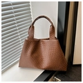 Detalle de un bolso de cuero marrón con textura tejida y asa estructurada de mano - Marrón