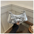 Detail of silver metallic shoulder bag with large bow and knot straps in a lifestyle setting - Silver