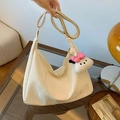 Large beige leather hobo bag with plush pendant on a glass table in a warm setting - Off-White with Pendant