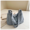 Close-up of light blue shoulder bag featuring cloud-texture leather and braided zipper - Blue