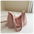 Close-up of pink textured crossbody bag with braided zipper pulls and fabric detail - Pink