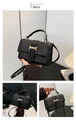 Detalle de bolso bandolera negro brillante con cierre H dorado y textura de piel sintética - Negro
