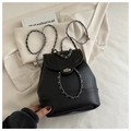 Detalle de mochila de cuero negro con cierre giratorio plateado y correa de cadena metálica - Negro