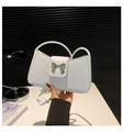 Primer plano de un bolso de hombro blanco con hebilla de lazo plateado metalizado - Blanco
