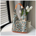 Detail einer floralen Canvas-Tragetasche mit orangefarbenem Rand auf weißem Tisch - Khaki