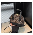 Nahaufnahme der Leoparden-Muscheltasche mit schwarzen Ledergriffen und Goldzipper - Schwarz