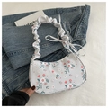 Nahaufnahme der floralen Umhängetasche mit Faltenriemen und Schleife auf Denim-Hintergrund - Grau