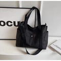 Close-up of black canvas tote bag with adjustable shoulder strap and utility pockets - Black