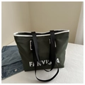 Dark green nylon tote bag with white lettering and sturdy black straps in a lifestyle set - Green