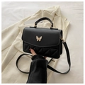 Bolso bandolera negro acolchado con cierre de mariposa blanca sobre chaqueta beige - Negro