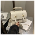 Close-up of white pleated leather handbag with gold buttons and cylindrical handle - White