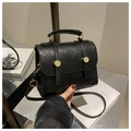 Detail of black textured crossbody bag with gold hardware and top handle design - Black