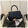 Elegant black saddle bag with woven handle and gold hardware shown in hand - Black