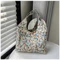 Detalle del bolso hobo floral sobre mesa con luz solar natural filtrada - Caqui
